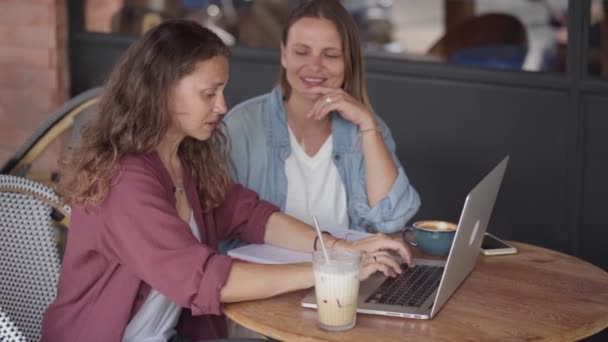 Gelukkig vrouwen werken samen met laptop in outdoor cafe — Stockvideo