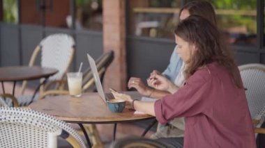 Açık kafede dizüstü bilgisayarla çalışan mutlu kadınlar.