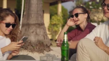 Dostlar sahilde oturur ve konuşmaktan zevk alırlar.