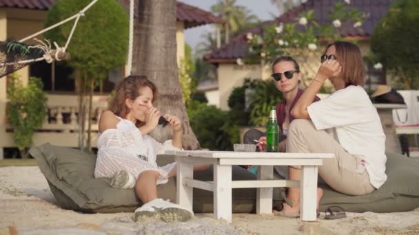 Amigos sentados en la playa y disfrutados hablando — Vídeos de Stock