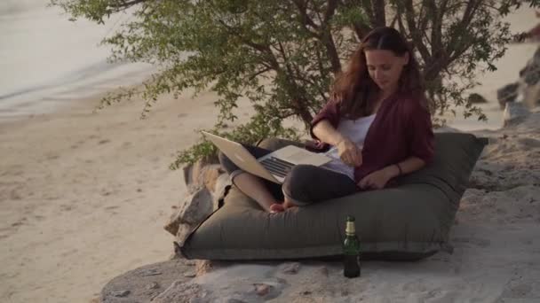 Meisje werkt met een laptop op het tropische strand — Stockvideo