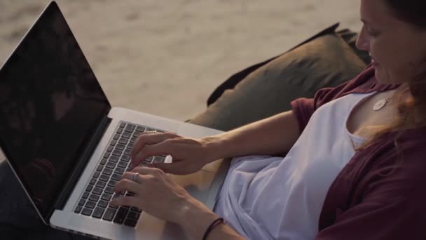 Девушка, работающая с ноутбуком на пляже — стоковое видео
