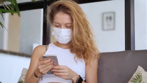 Jovem mulher vestindo máscara protetora branca usar smartphone — Vídeo de Stock