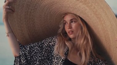 Güzel kız kumsalda büyük hasır bir şapka takıyor.