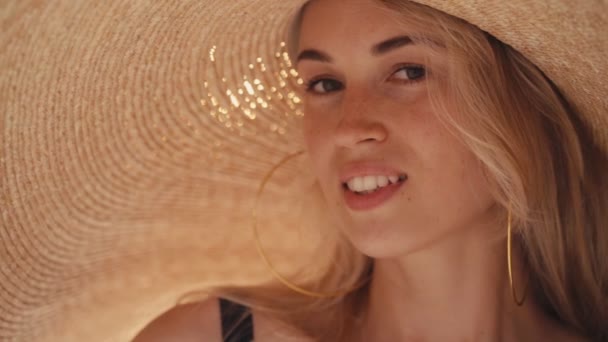Όμορφο κορίτσι φορώντας μεγάλο ψάθινο καλοκαιρινό καπέλο στην παραλία — Αρχείο Βίντεο
