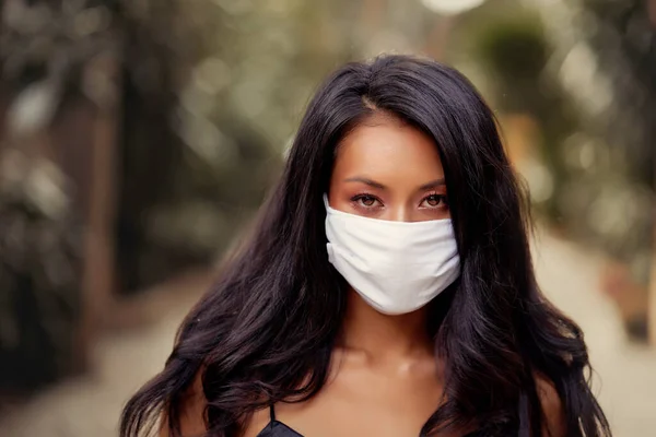 Cerrahi maske takan güzel bir Asyalı kadın virüse karşı koruyucu. Beyaz tıbbi maskeli Asyalı bir model.