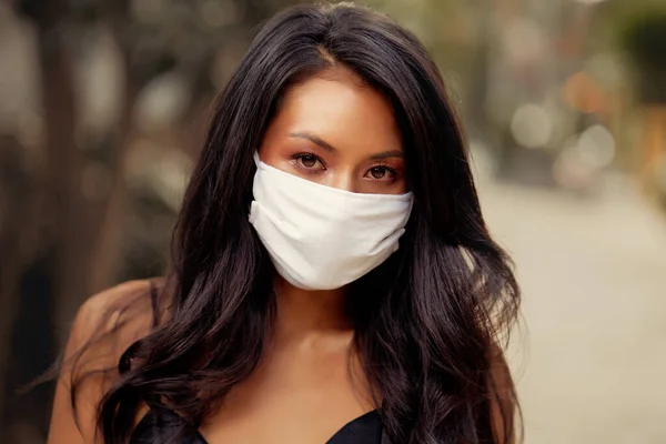 Cerrahi maske takan güzel bir Asyalı kadın virüse karşı koruyucu. Beyaz tıbbi maskeli Asyalı bir model.