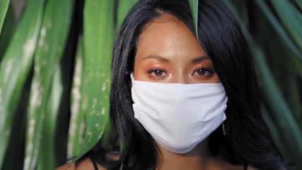 美しいアジアの女性は、ウイルスに対する外科的フェイスマスク保護を身に着けている。ホワイトメディカルマスクとファッションアジアモデル — ストック動画