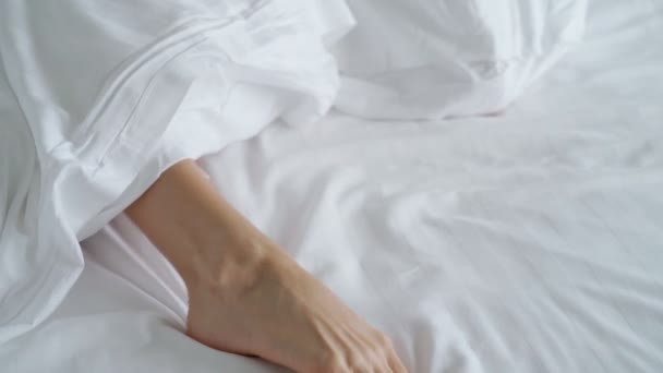 Sabahları yatakta uyanırken battaniyenin altında kadın ayaklarının yakınlaşması. — Stok video