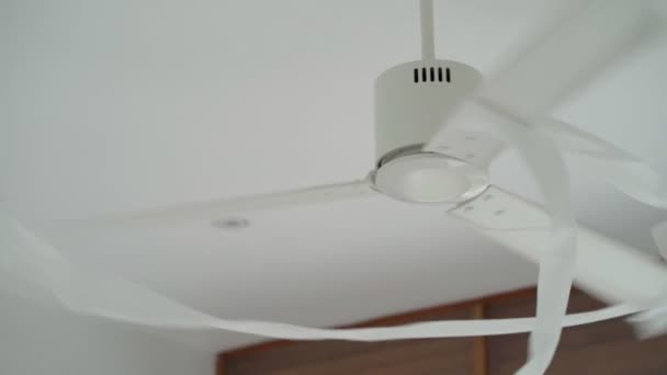 Toilet paper is wound on a white metal ceiling fan — Stock Video