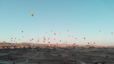 Goreme 'in 4K hava görüntüsü. Vadilerin üzerinde uçan renkli sıcak hava balonları. Ünlü şehir Kapadokya, Türkiye.