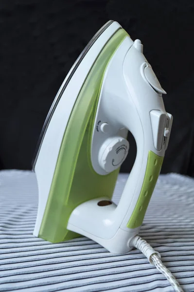 Electric flatiron with green body on striped fabrics — Stock Photo, Image