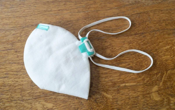 Ahşap masada beyaz tıbbi maske. Salgın sırasında solunumun korunması için steril tesis