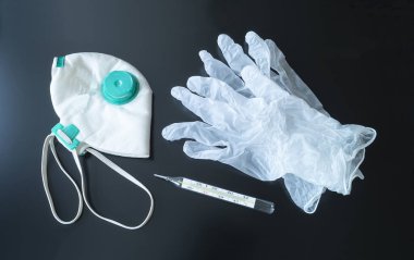 Siyah arka planda eldiven, maske ve termometre. Virüsün tedavisi için tıbbi denekler