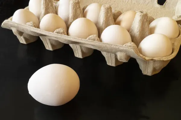 硫黄の鶏の卵は板紙から梱包する 暗い背景に飼料の新鮮な製品 — ストック写真
