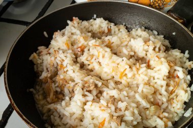 Tavada kızarmış et ve sebzeli pilav. Kırbaçla sıcak, lezzetli bir akşam yemeği