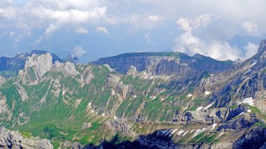 Viev from the top the Saentis to the steep rock faces of the Alpstein-Massif, snow fields, overcast sky