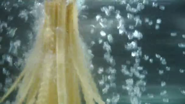 La pasta cae en agua hirviendo. Burbujas de agua. primer plano dolly tiro. Movimiento lento — Vídeos de Stock