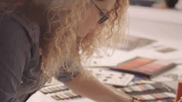 Attractive fashion designer sketching at table in her studio — Stock Video