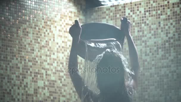 Hermosa mujer lava bajo el chorro de agua su pelo largo. Movimiento lento — Vídeos de Stock