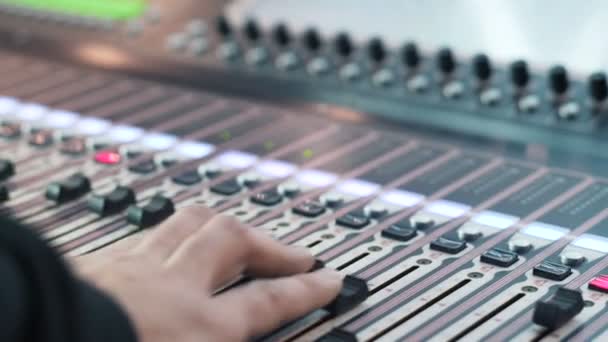 Ingeniero de audio trabajando en una consola profesional, faders en movimiento, mezclando música — Vídeos de Stock