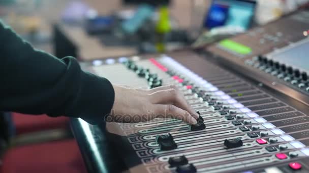 Ingeniero de audio trabajando en una consola profesional, faders en movimiento, mezclando música — Vídeo de stock