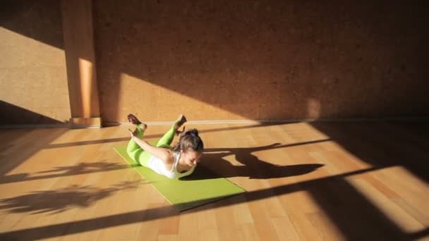 Bir sporcumuz streç bacaklarını ve geri dışarı egzersiz mindere uzan — Stok video