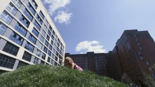 Une adorable petite fille sourit et se précipite sur la colline verte de près — Video