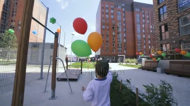 Madres pequeño hijo caminando con globos de colores en la calle — Vídeos de Stock