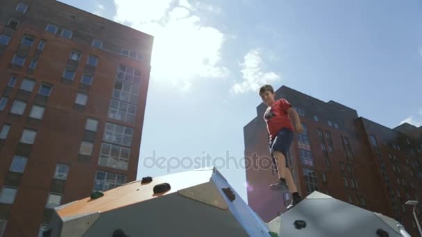 Een kleine jongen in sportieve concept plaatsen lopen en springen — Stockvideo