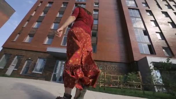 アパルトへゆっくり歩いて赤いロング スカートの若い女性 — ストック動画