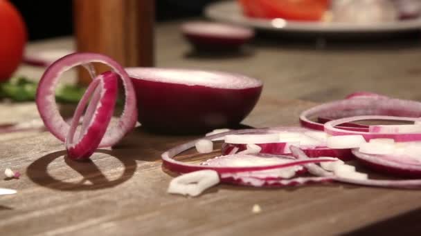 Rote Zwiebelringe fallen langsam auf das Schneidebrett — Stockvideo