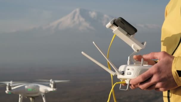 Mannen händerna styra flygande quadcopter nära mountain — Stockvideo