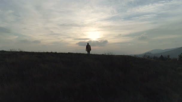 Un caminante caminando en la colina hasta el lago al atardecer — Vídeo de stock