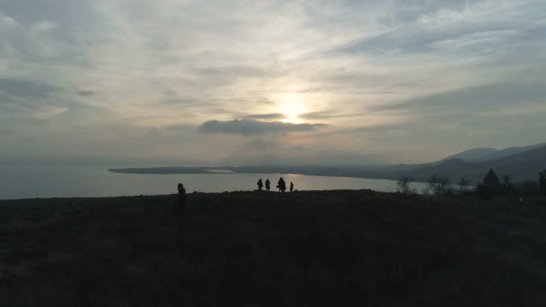 Vrienden lopen in het sunset hill naar de kust — Stockvideo