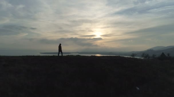 Egy kirándulás ember séta a hegyen a tó naplementekor — Stock videók