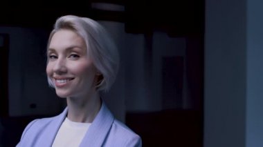 30 'lu yaşlardaki kendine güvenen sarışın çekici iş kadını kameraya gülümsüyor.