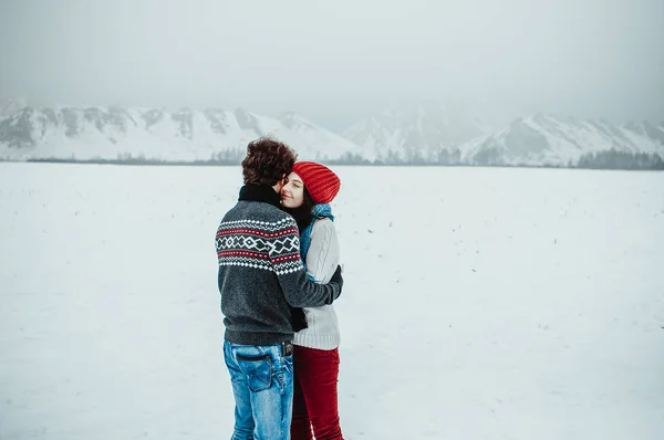 Парень с девушкой, гуляющей по горам зимой, смеется — стоковое фото
