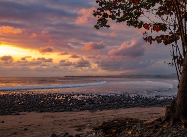 Günbatımı bir çakıl plajı üzerinde