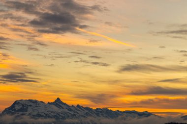 Karlı dağlar üzerinden canlı turuncu günbatımı