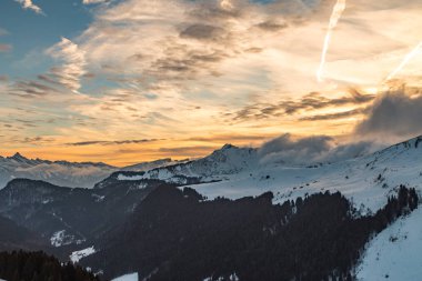 Karlı dağlar üzerinden canlı turuncu günbatımı