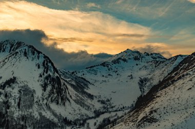 Karlı dağlar üzerinden canlı turuncu günbatımı
