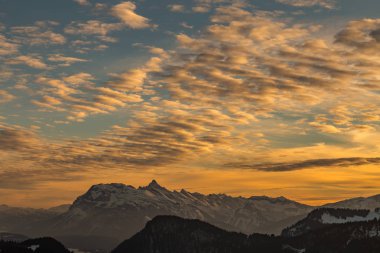 Karlı dağlar üzerinden canlı turuncu günbatımı