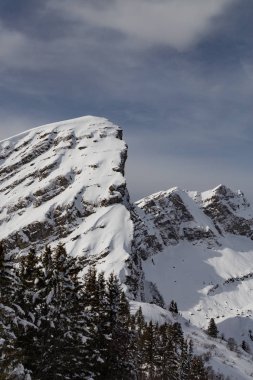 Kar ve bulutlar ve ağaçları ile kaplı dağları