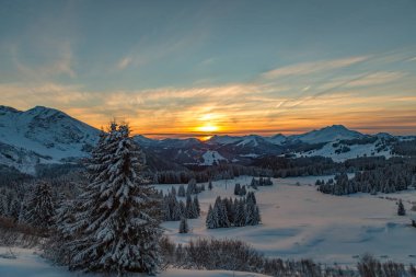 Beyaz bir karlı dağ aralığı boyunca canlı günbatımı