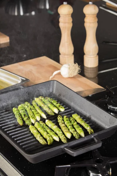 Une poignée d'asperges vertes à cuire et à cuire à la vapeur sur une plaque de gril — Photo