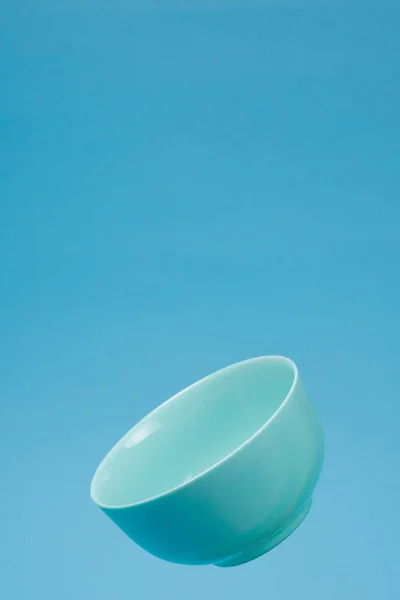 A blue ceramic mattle deep bowl for breakfast flying on blue bac — Stock Photo, Image