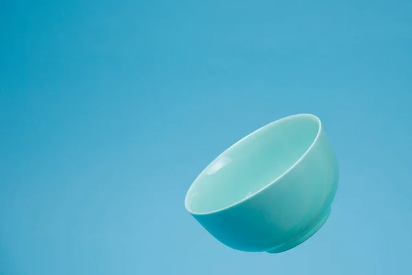 Uma tigela de cerâmica azul mattle profunda para o pequeno-almoço voando em bac azul — Fotografia de Stock
