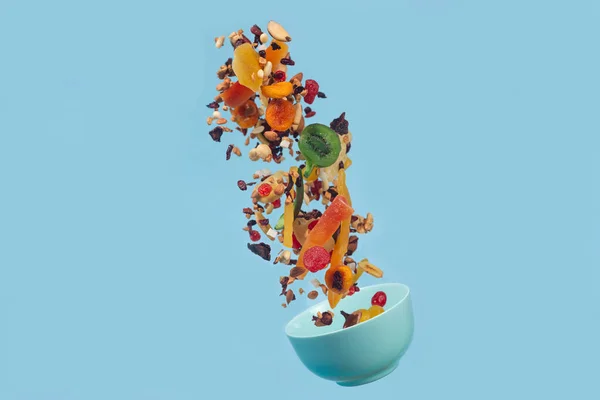 푸른 세라믹 그릇 위를 날고 있는 말린 과일 과 견과류 — 스톡 사진