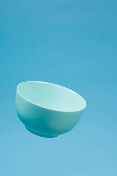 A blue ceramic mattle deep bowl for breakfast flying on blue bac — Stockfoto